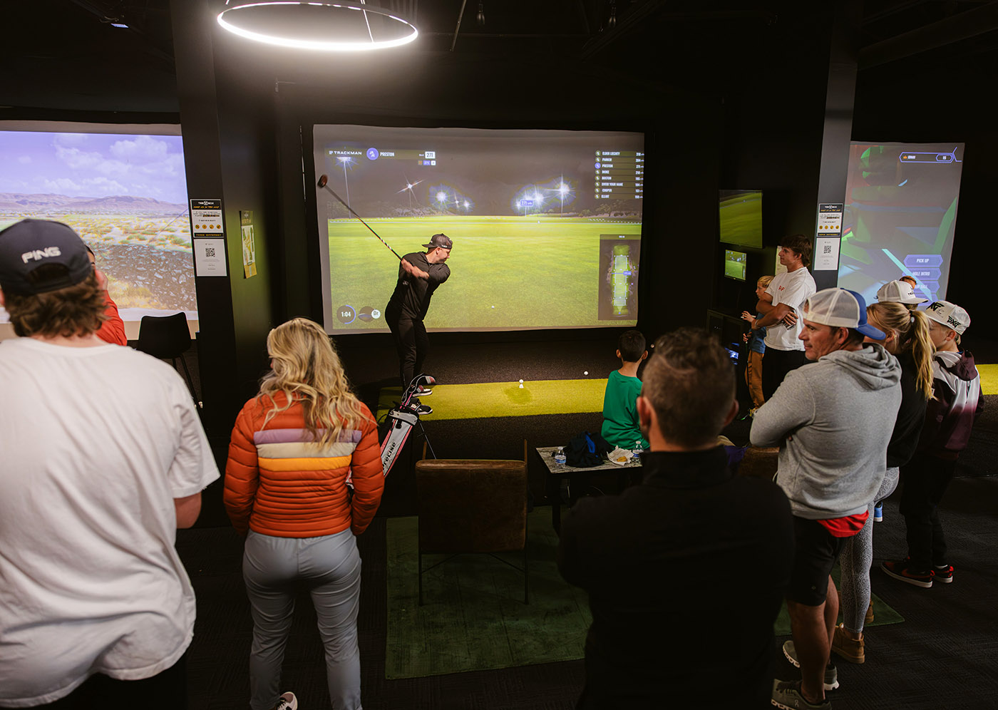 A large group having fun and playing golf at Tee Box, one of the top adult birthday party places.